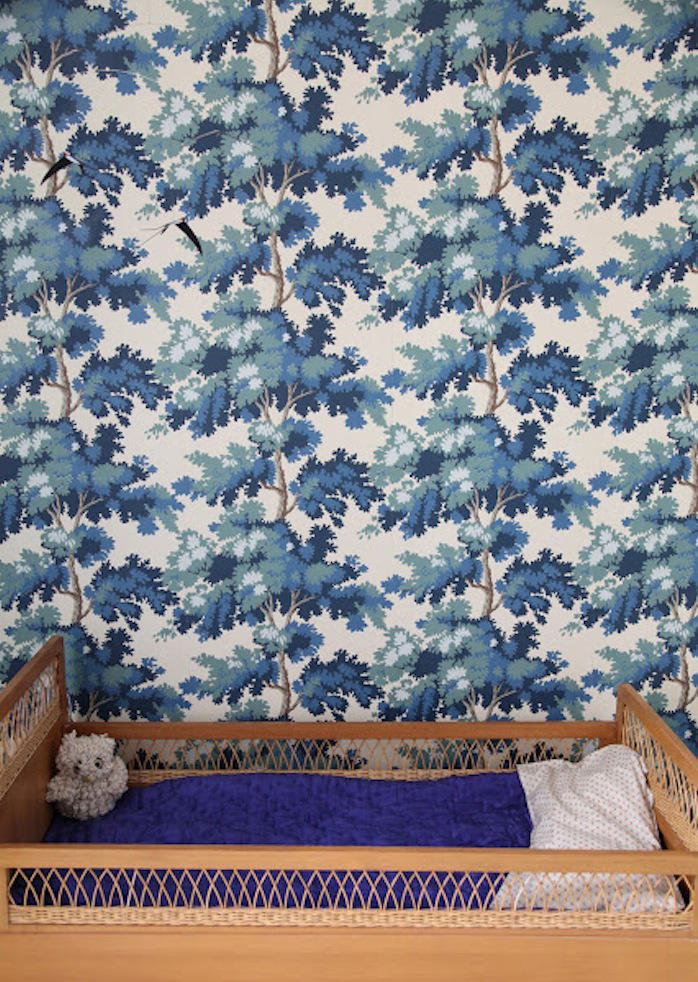 El estampado de arboles azules amplia visualmente el alto de los techos de esta habitación infantil